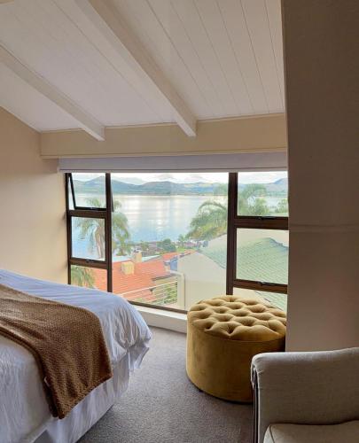 a bedroom with a large window with a view of the water at Hoyozela in Hartbeespoort