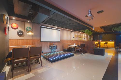 a room with a projector screen and a table and chairs at Hotel Apsara in Kizhake Chālakudi