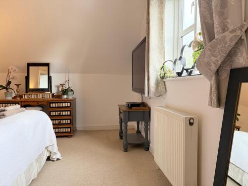 a bedroom with a bed and a window and a television at Silsoe Cottage B&B - Woodland View Room in Silsoe