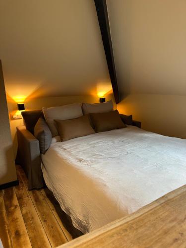 a bedroom with a large white bed with two lamps at La fagnette in Jalhay