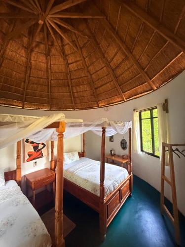 a bedroom with two beds and a straw roof at Daga Tented Camp in Mikumi
