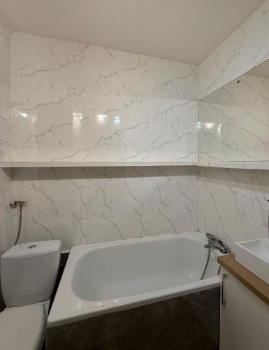 a bathroom with a tub and a toilet and a sink at Apartament Mazury in Kętrzyn