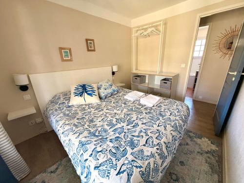 a bedroom with a bed with a blue and white bedspread at Maison villa Lilou, Pierre et vacances, avec piscine, vue sur le golf, plage à 10 min à pied in Moliets-et-Maa