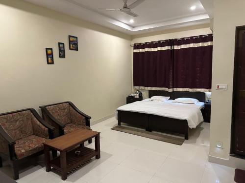 a bedroom with a bed and a table and chairs at Hotel Meghdoot in Bhadohī