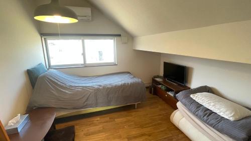 a bedroom with a bed and a couch and a window at B&BHOUSE FAM in Ichinomiya