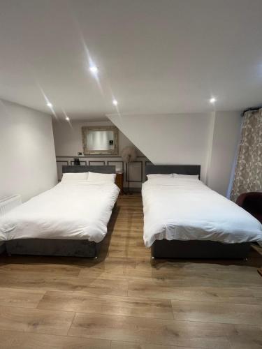 two beds in a room with white sheets at The Dublin Packet Room No6 in Holyhead