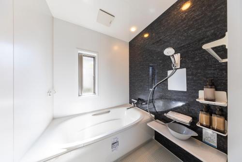 a bathroom with a tub and a sink at YAMAKATSU Hotel in Dazaifu