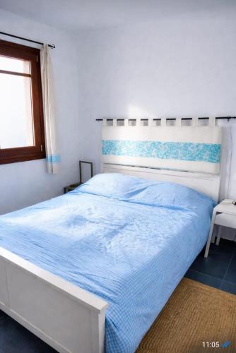 a white bedroom with a white bed with blue sheets at Casa Zeralda, privater Pool in Budoni