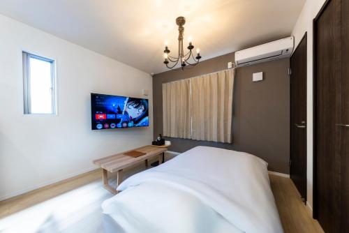 a bedroom with a bed and a tv on the wall at YAMAKATSU Hotel in Dazaifu