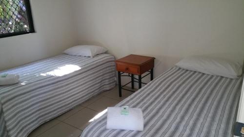 two beds in a room with a night stand and a table at Atherton Holiday Park in Atherton