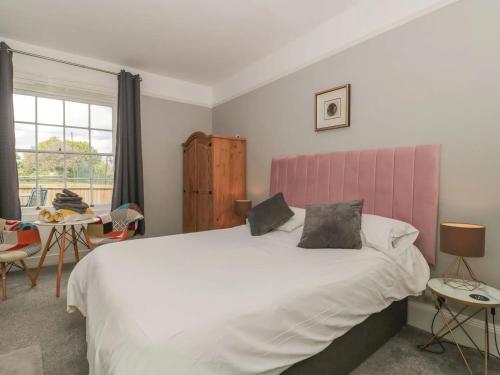 a bedroom with a large bed with a pink headboard at Countryside Annexe, with hottub, sleeps up to 4 in Durston