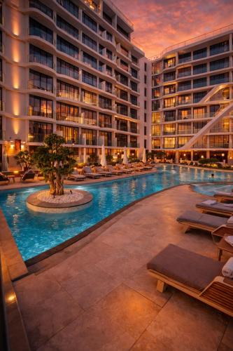 a large swimming pool with lounge chairs in a building at Arjan Luxury Studio Pool View Near Miracle Garden in Dubai