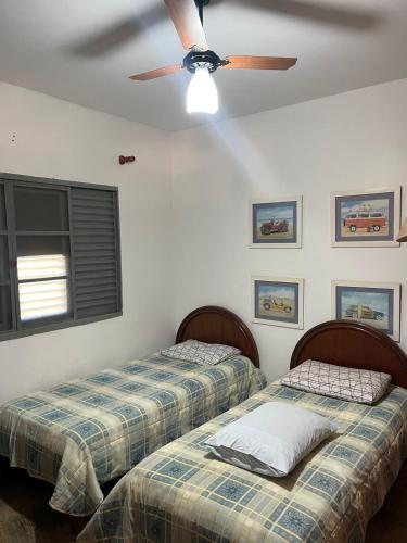two beds in a room with a ceiling fan at Chacara Vila Bella in Bebedouro