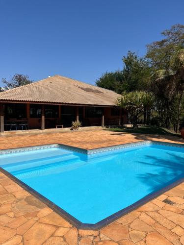 a large blue swimming pool in front of a house at Chacara Vila Bella in Bebedouro