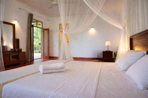 a bedroom with a large white bed and a window at Bluewind Hotel in Tangalle