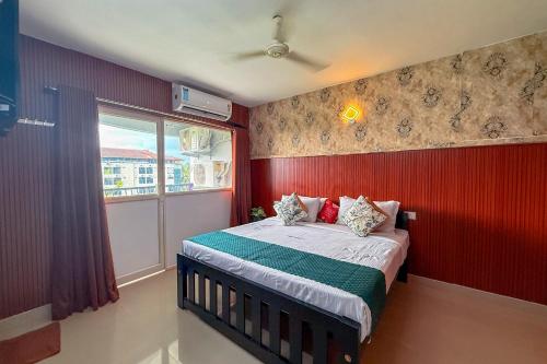 a bedroom with a bed with red walls and a window at Sancta Maria - Accomodation For Groups -Cochin Airport in Nedumbassery