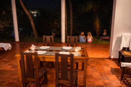 a wooden table with chairs and people in the background at Bluewind Hotel in Tangalle