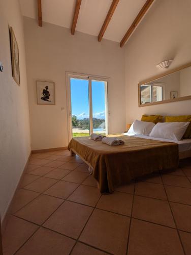 a bedroom with a large bed and a large window at Villa A Macchia, piscine et vue sur Bonifacio in Bonifacio
