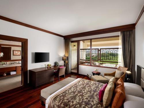 a bedroom with a bed and a desk and a tv at Jaypee Greens Golf and Spa Resort in Greater Noida