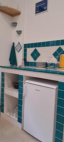 a kitchen with blue and white tiles and a refrigerator at ortigia adriana suite in Syracuse
