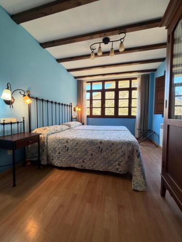 a bedroom with a bed and a table and windows at Casas Rurales Las Corradas in Éndriga