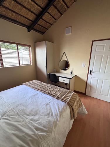 a bedroom with a bed and a desk with a mirror at Countryview Chalet in Benoni