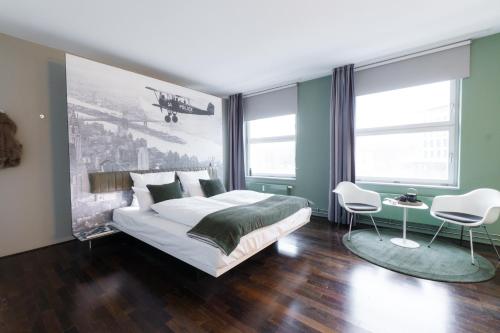 a bedroom with a bed and two white chairs at Motorworld Inn Hotel Böblingen in Böblingen