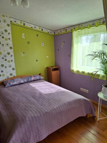 a bedroom with a purple bed and a window at Po Beržu in Molėtai