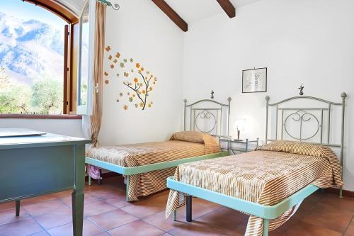a room with two beds and a table and a window at Villa Le Sterlizie in Castellammare del Golfo