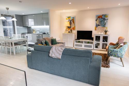 a living room with a blue couch and a kitchen at OPORTO GUEST - Maia House in Porto