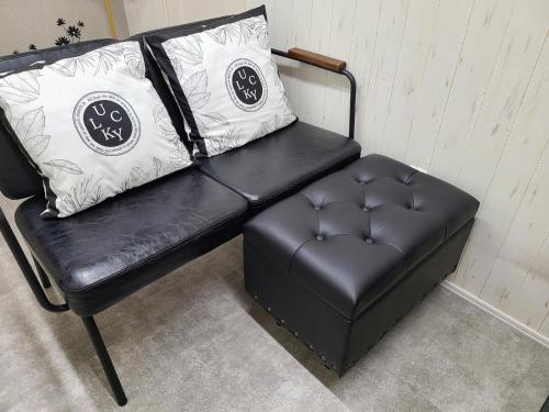 a black leather couch with a pillow and a stool at Greci Art Tokyo-Kinshicho Area Private room- in Tokyo
