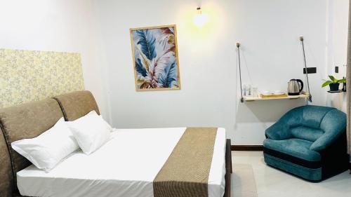 a bedroom with a bed and a blue chair at Infinity Villa in Anuradhapura