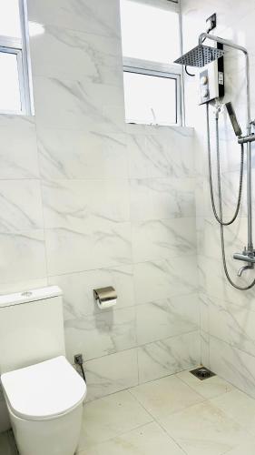 a white bathroom with a shower and a toilet at Infinity Villa in Anuradhapura