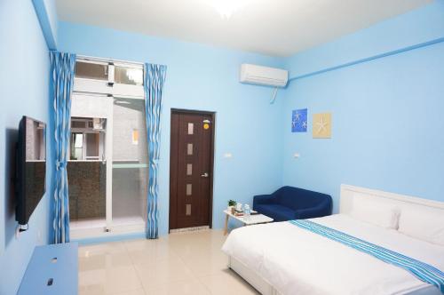 a blue room with a bed and a chair and a window at 強國特調民宿 in Taitung City