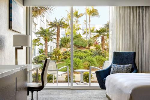 a hotel room with a bed and a balcony with palm trees at Ventura Beach Marriott in Ventura