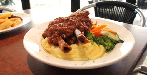 a plate of food with pasta and broccoli on a table at Rocky Glen Hotel Motel Gladstone in Gladstone
