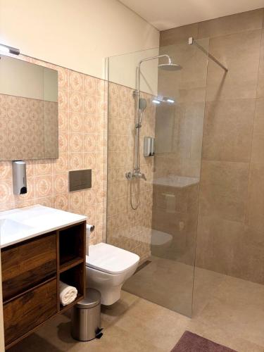 a bathroom with a toilet and a glass shower at Casa Germano in Sabugal