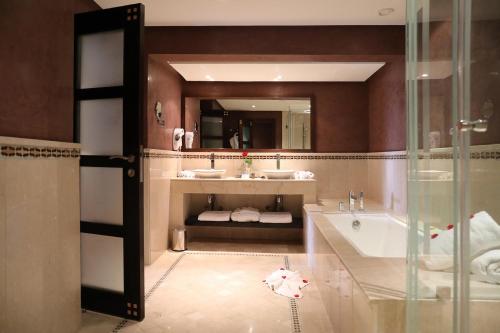 a bathroom with two sinks and a tub and a mirror at Kenzi Menara Palace & Resort in Marrakesh