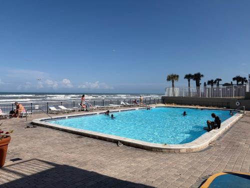a swimming pool with people in it next to the beach at Single, Double or Quad Oceanview Studios - Direct Beach Access, Oceanfront Pool & Tiki in Daytona Beach Shores