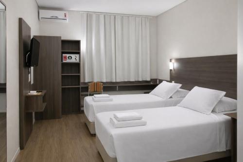a hotel room with two beds and a television at DE STEFANI HOTEL in Portão