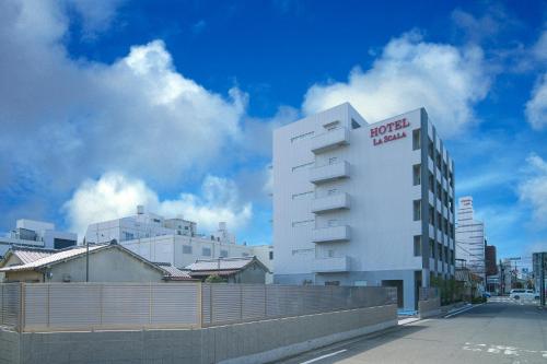a white building with a red hotel sign on it at HOTEL LASCALA in Wakayama