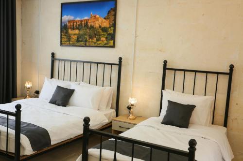 a bedroom with two beds and a painting on the wall at The Castle İnn in Mardin