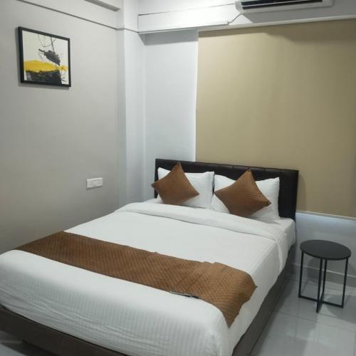 a bedroom with a bed with brown and white pillows at Lexora Hotel in Chharodi