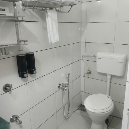 a white bathroom with a toilet and a shower at Lexora Hotel in Chharodi