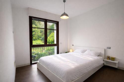 a white bedroom with a large bed and a window at Acqua & Luce in Meina