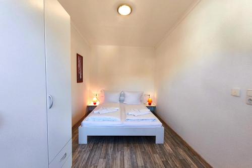 a small bedroom with a bed and two lamps at Ferienwohnung Sonnenblick in Loddin