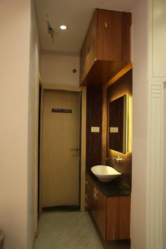 a bathroom with a sink and a door with the word manifestation at Samyak Stay in Ujjain