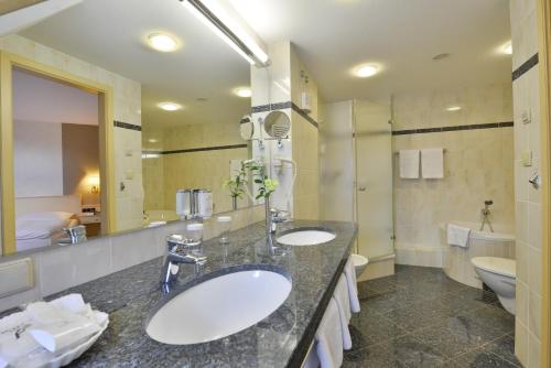 a bathroom with two sinks and a large mirror at Ringhotel Weißer Hirsch in Wernigerode