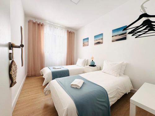two beds in a room with white and blue at Casa do Mar - Reconnect - T2 com pátio junto à praia in Ovar