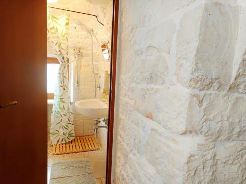 a bathroom with a sink and a white stone wall at B&B La Rosa dei Trulli Alberobello in Alberobello